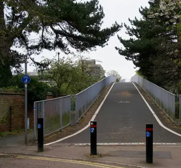 Three bollards blocking the entrance to a shared path, making wheelchair access difficult