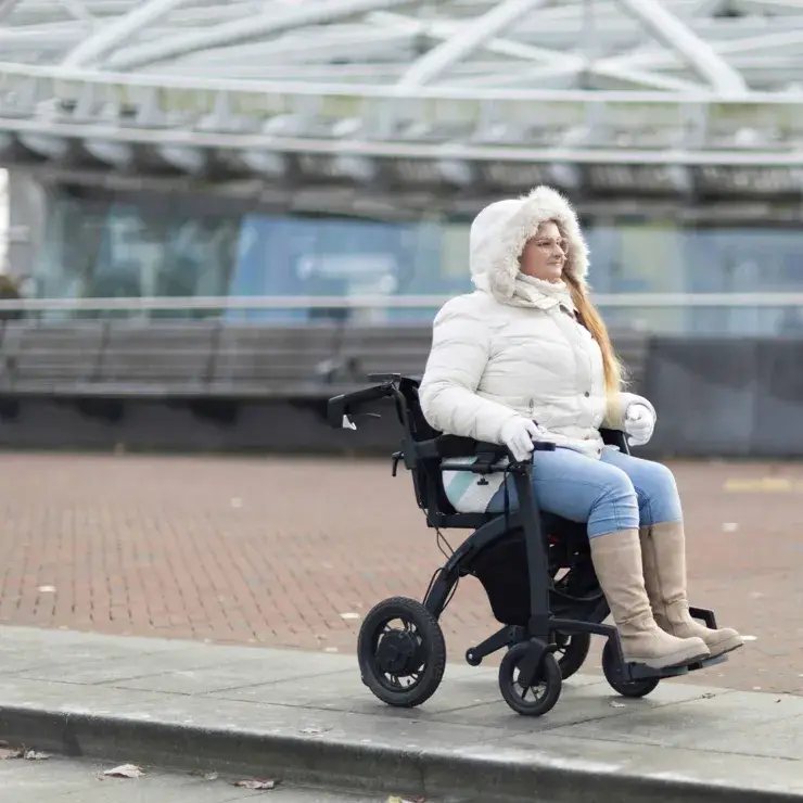 Wheelchair user on a pavement with no accessible dropped kerb to cross the road