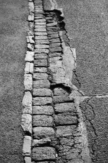 Broken and uneven kerb surface that prevents safe wheelchair access across the road